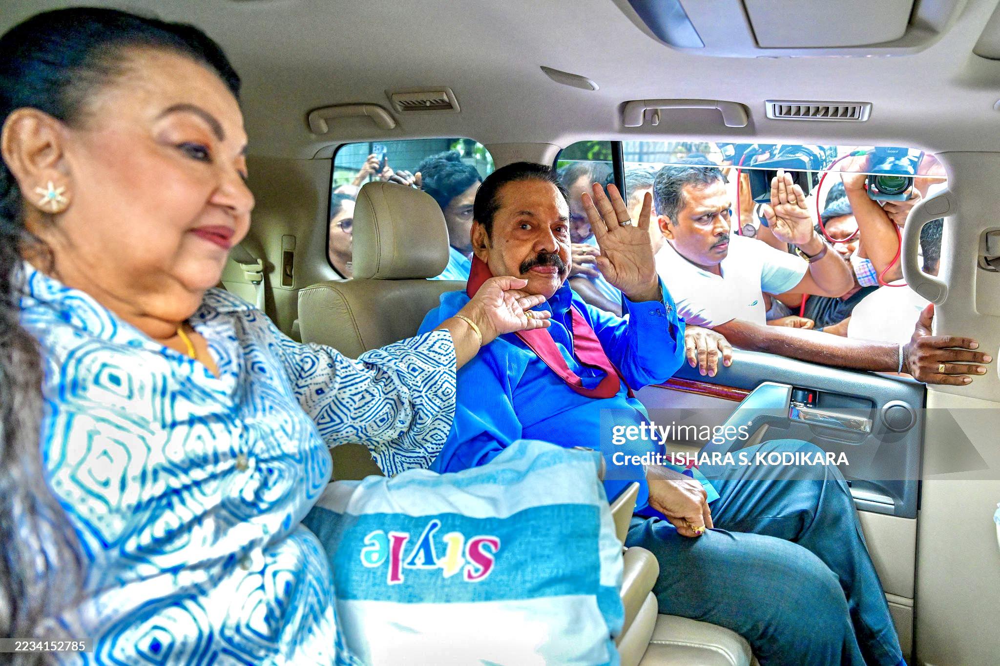 Sri Lanka's former president Mahinda Rajapaksa (R), along with his wife Shiranthi Rajapaksa, gestures as they vacate their official residence in Colombo on September 11, 2025. Sri Lanka's parliament voted on September 10, to evict former president Mahinda Rajapaksa and two others from state-owned mansions under austerity measures introduced by the new leftist government. (Photo by Ishara S. KODIKARA / AFP) (Photo by ISHARA S. KODIKARA/AFP via Getty Images)          